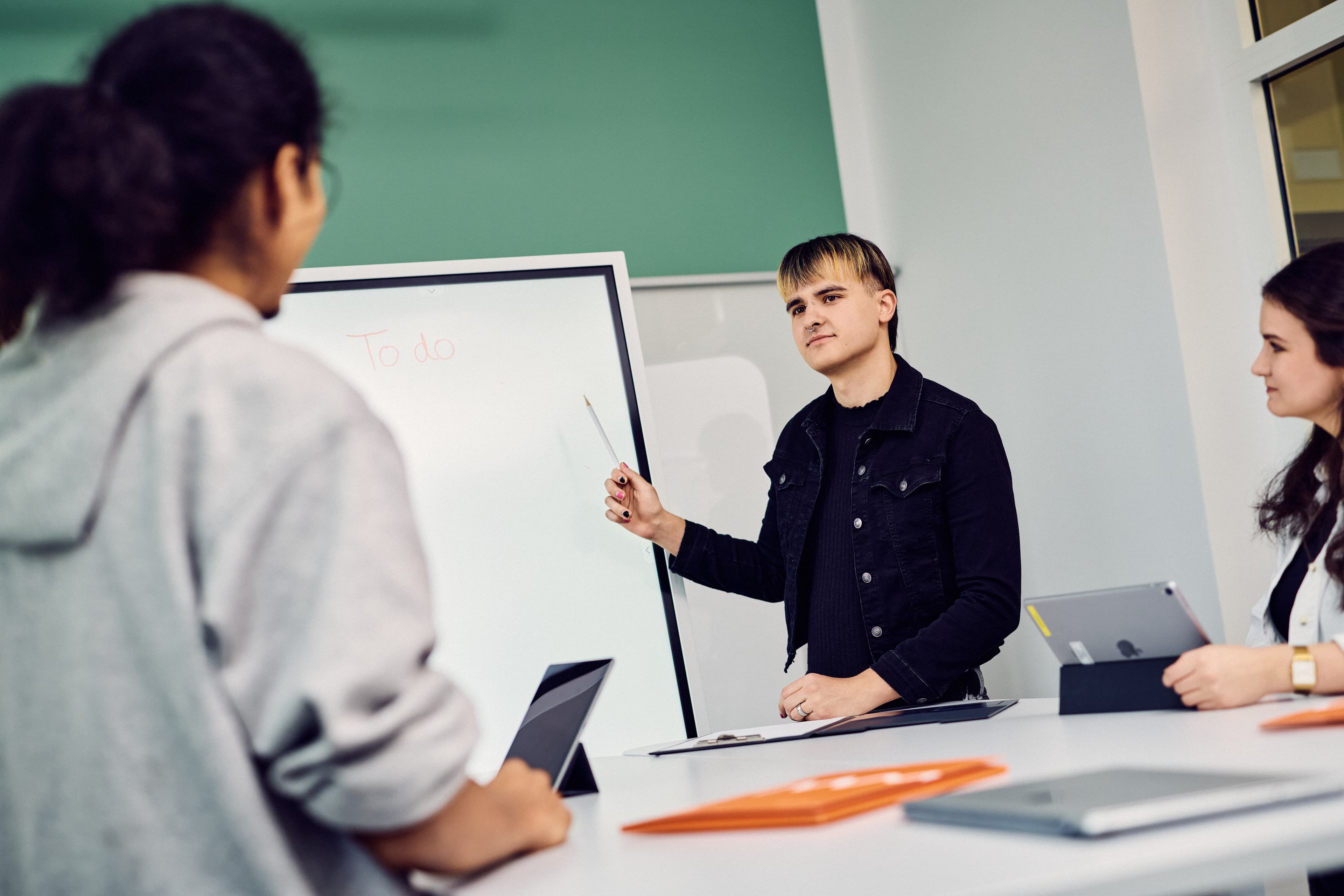 One person showing two IWM employees something on a whiteboard
