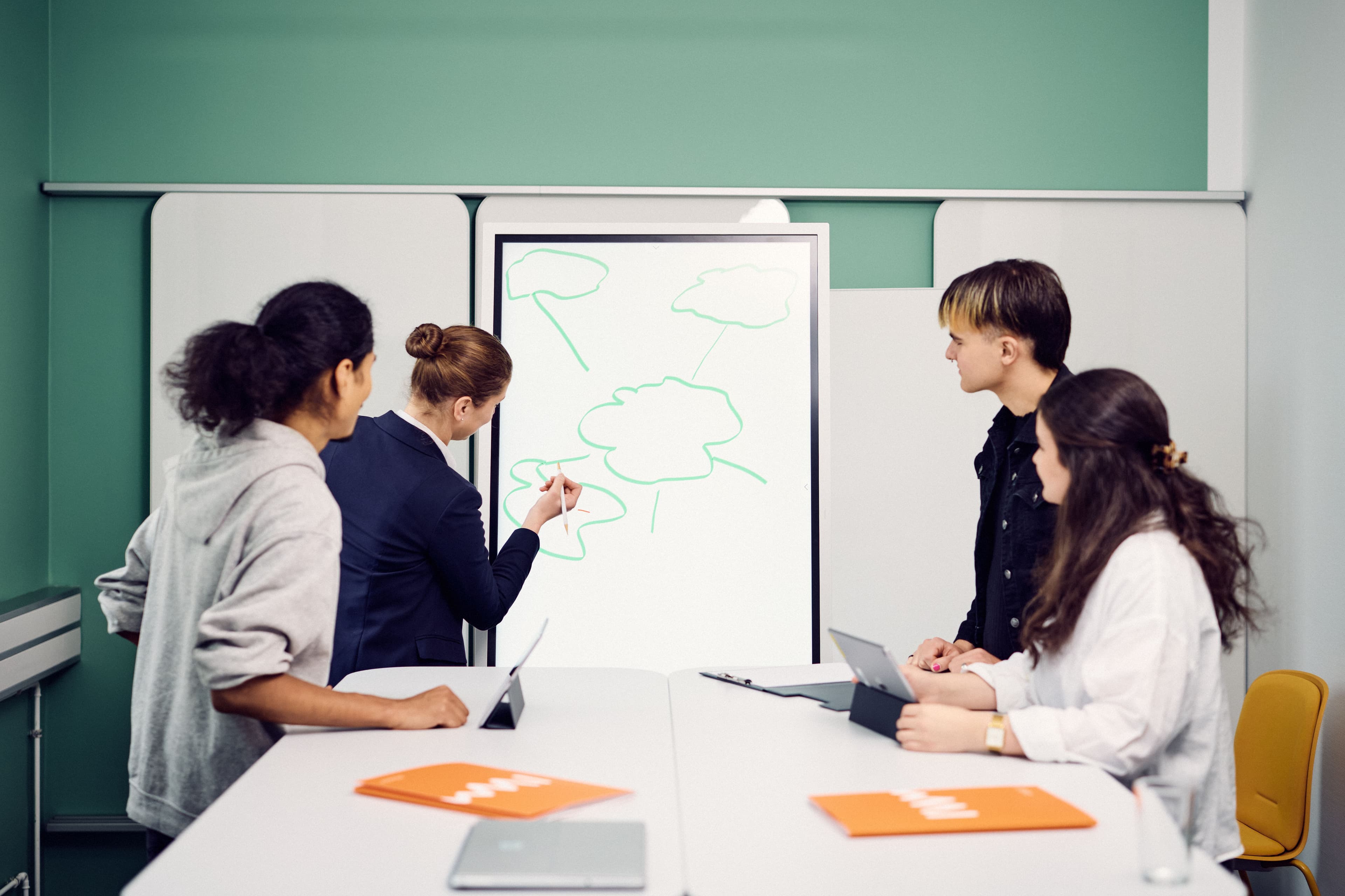 Four IWM employees brainstorming together and one person draws a mind map on a whiteboard