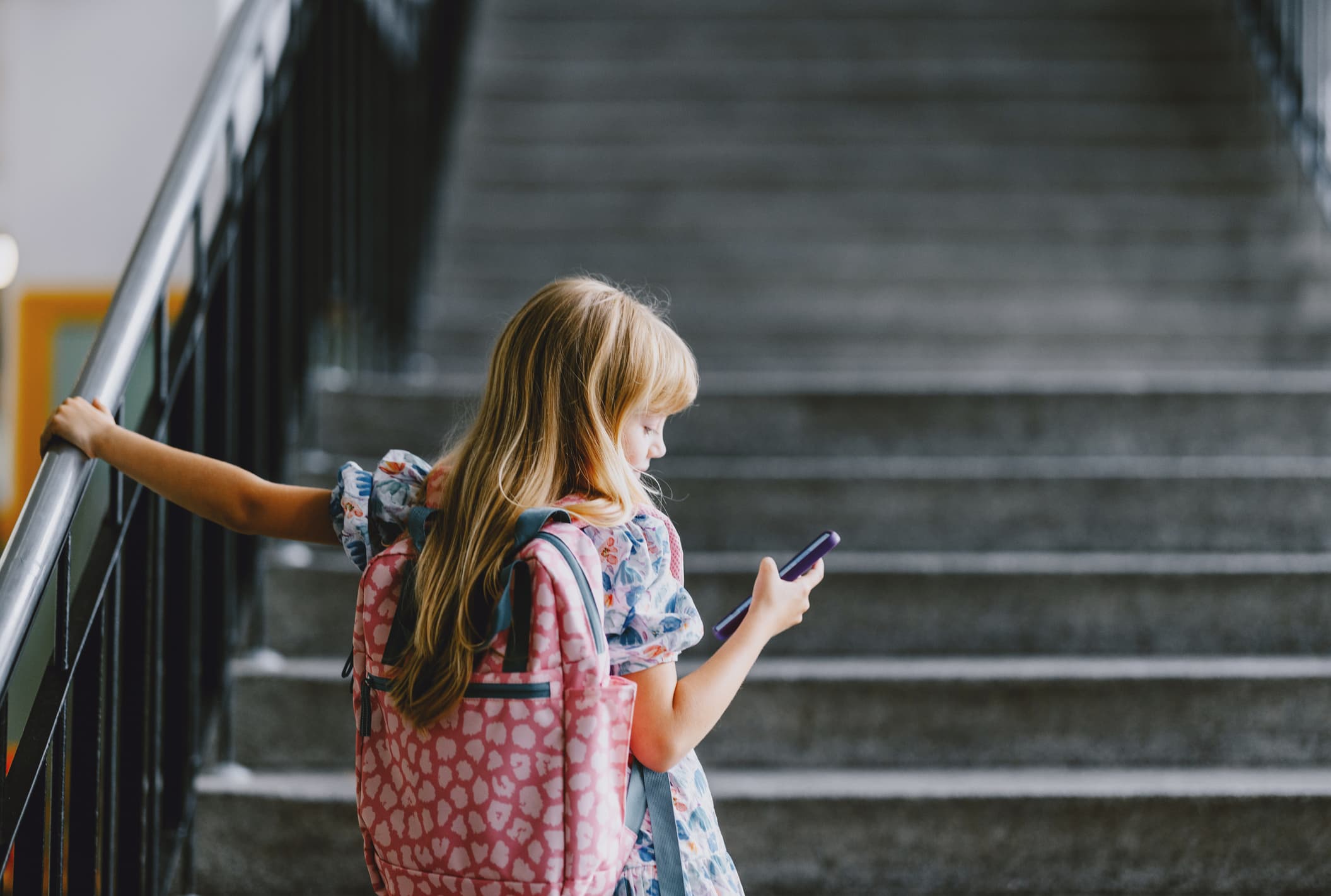 Child with smartphone in front of a staircase