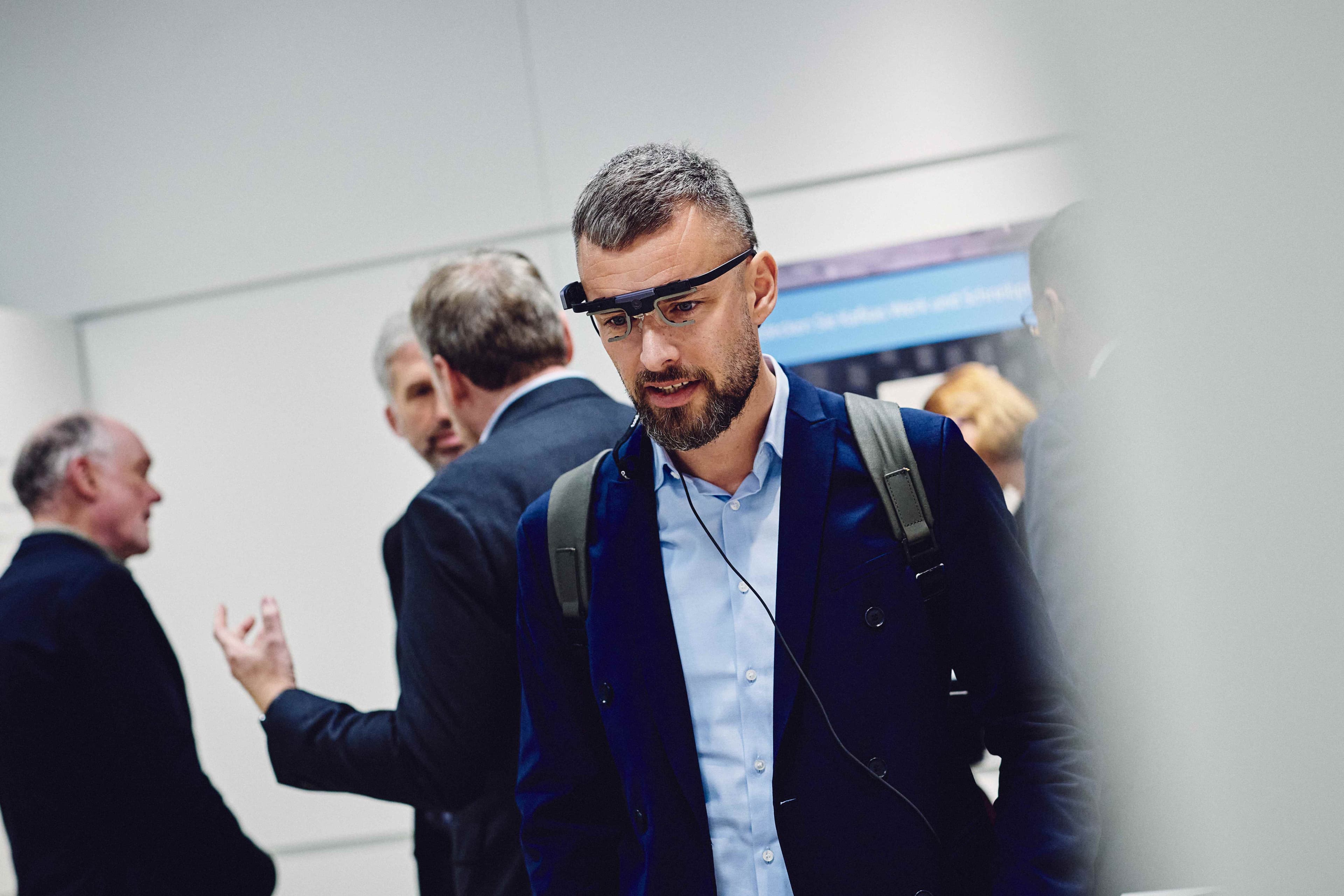 A visitor tests an interactive application using smart glasses in the MuseumLab, while other guests are visible in the background